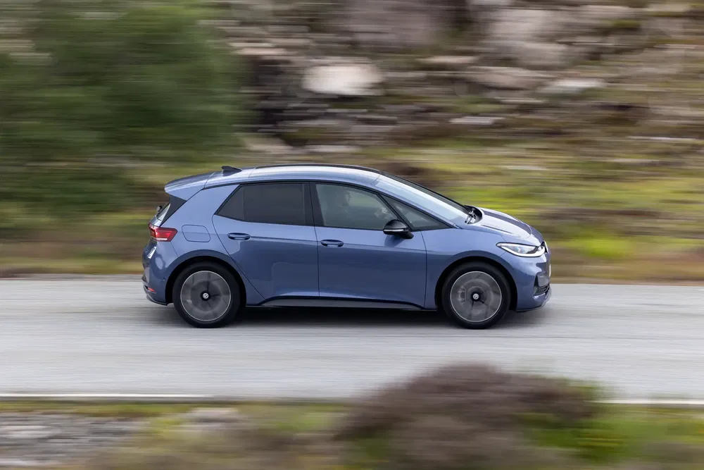 Blauwe Volkswagen ID.3 elektrische auto rijdend op een schilderachtige weg.