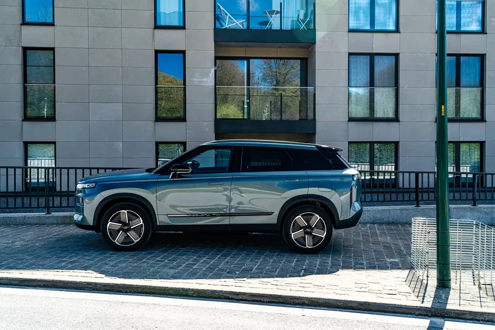 Moderne Aiways U5 SUV geparkeerd voor stedelijk gebouw met glazen ramen.
