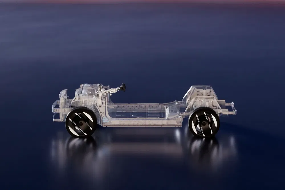 Châssis transparent de véhicule électrique avec plateforme et roues noires sur fond sombre.