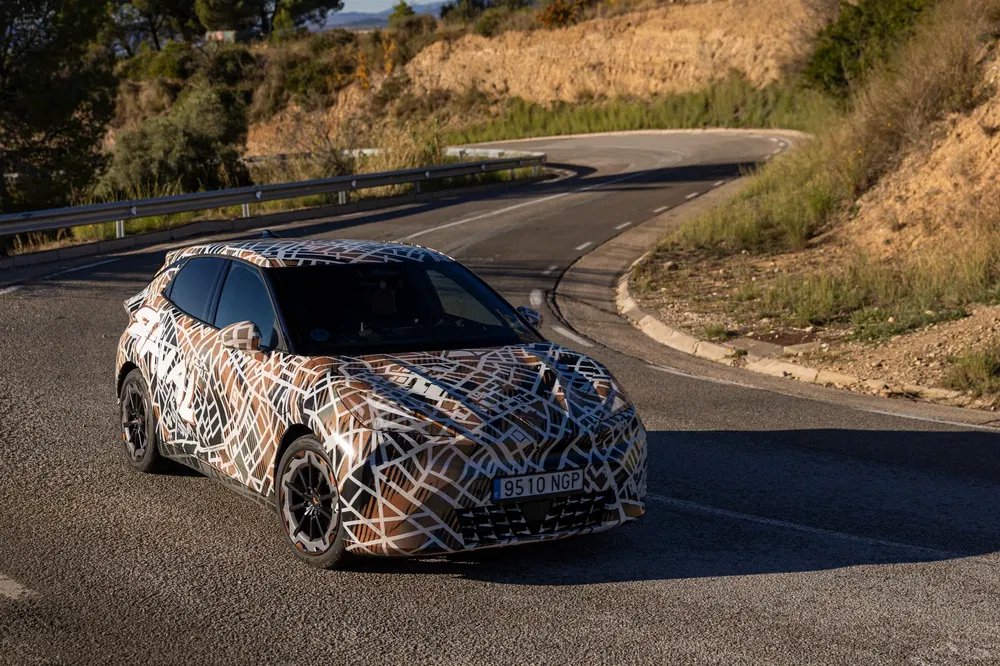 {"fr":"Prototype de SUV camouflé en test sur route sinueuse en montagne.","nl":"SUV-prototype met camouflage tijdens testrit op bochtige bergweg."}