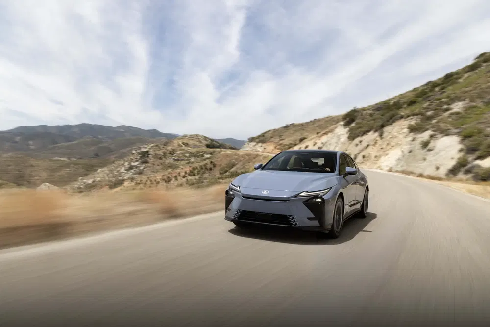 Voiture Lexus sur une route montagneuse, ciel nuageux en arrière-plan.