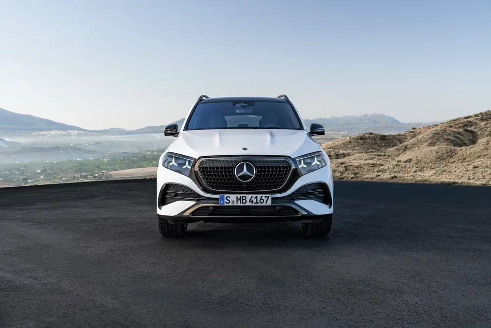 SUV Mercedes-Benz GLE blanc devant paysage montagneux, ciel dégagé en arrière-plan.