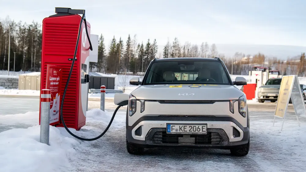 Kia EV6 électrique chargée à une borne rapide rouge en hiver enneigé.