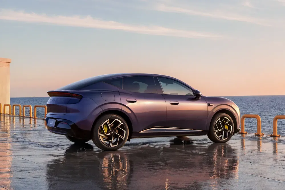 SUV électrique BYD Tang violet, stationné près de l'océan au coucher du soleil.
