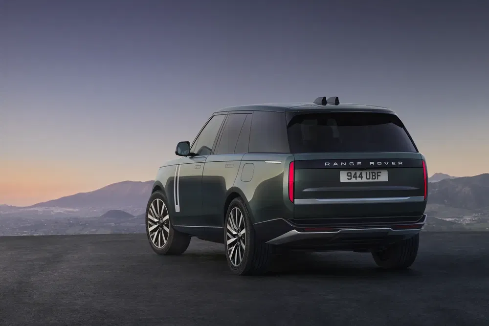 Range Rover moderne silhouette arrière, coucher de soleil, paysage montagneux en arrière-plan.