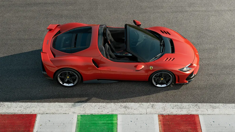 Ferrari rouge sur circuit, capote ouverte, pneu noir, bordure drapeau italien.