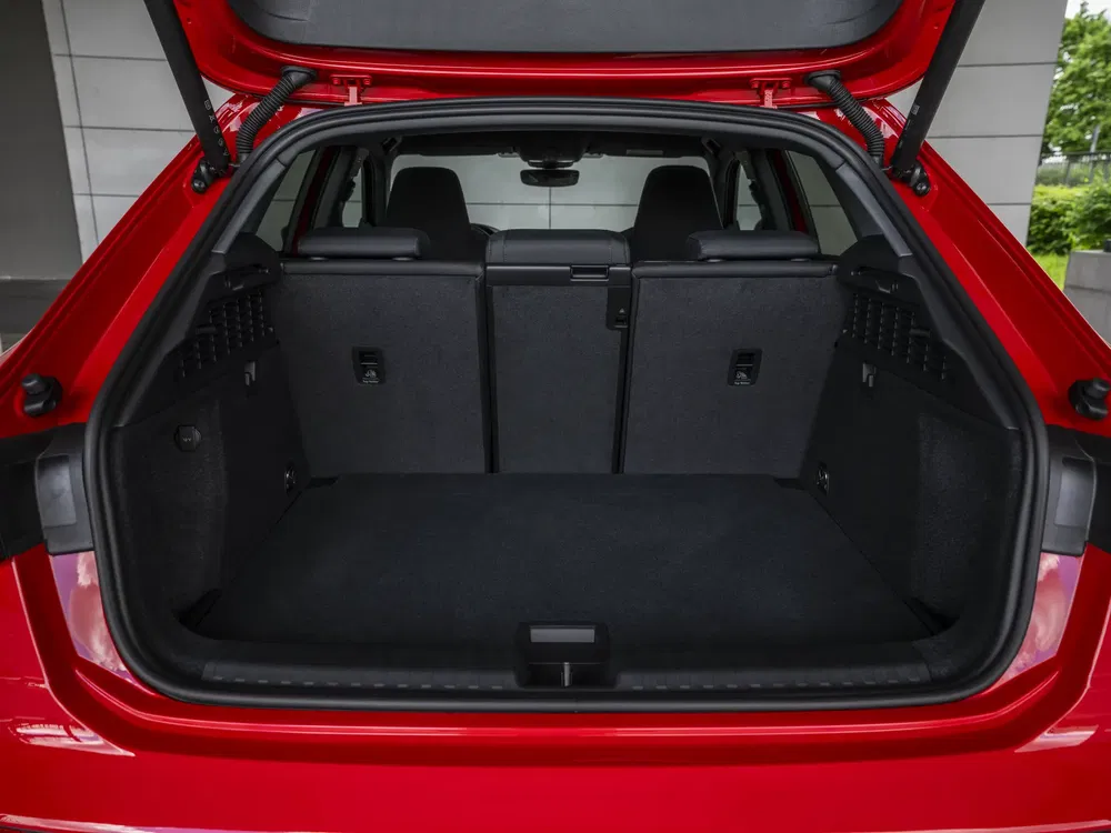 Coffre spacieux d'une voiture rouge, sièges arrière rabattus pour plus de capacité.