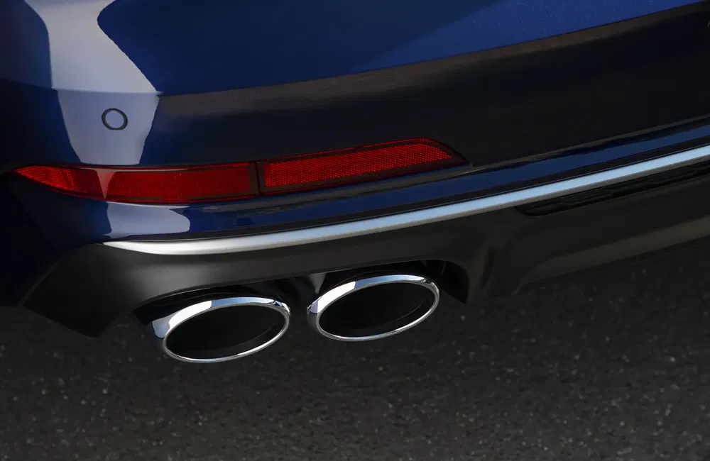 {"fr":"Double sortie d'échappement chromée sous pare-chocs d'une voiture bleue sur chaussée.","nl":"Dubbele chromen uitlaat onder bumper van een blauwe auto op asfalt."}