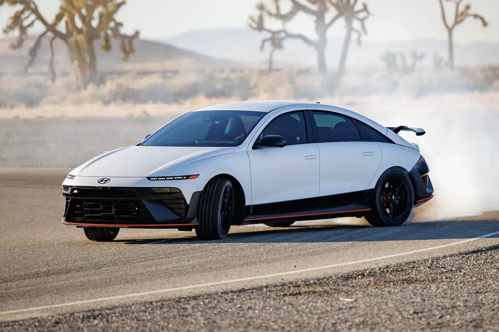 Hyundai Ioniq 6 effectuant un dérapage sur une route désertique, laissant une traînée de fumée.