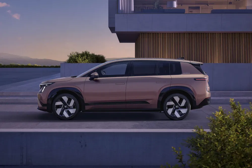 Vue latérale d'un Renault Scenic 2024 moderne devant un bâtiment minimaliste au crépuscule.
