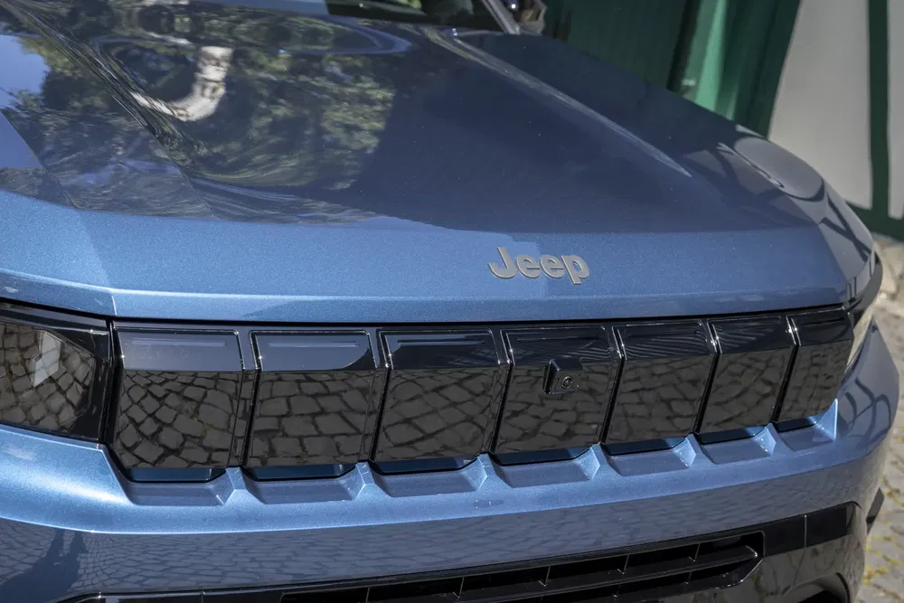 Capot d'une Jeep bleu métallisé avec calandre noire distinctive.