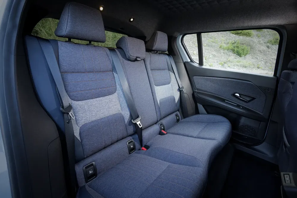 Intérieur d'une voiture avec sièges arrière rembourrés gris et ceintures de sécurité noires.