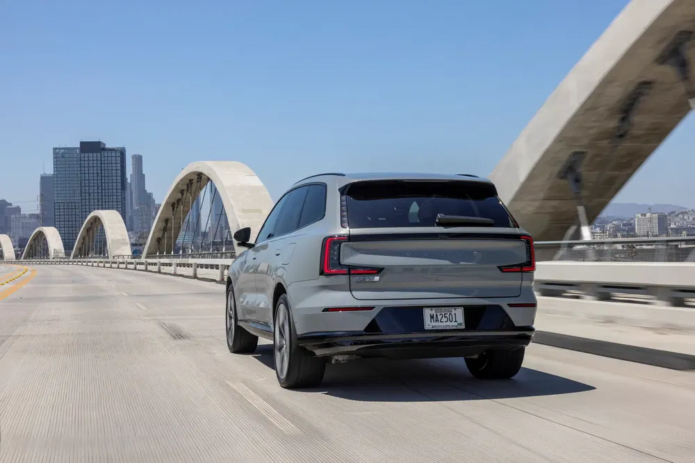 Volvo SUV op modernistische brug, een stad op de achtergrond en heldere lucht.