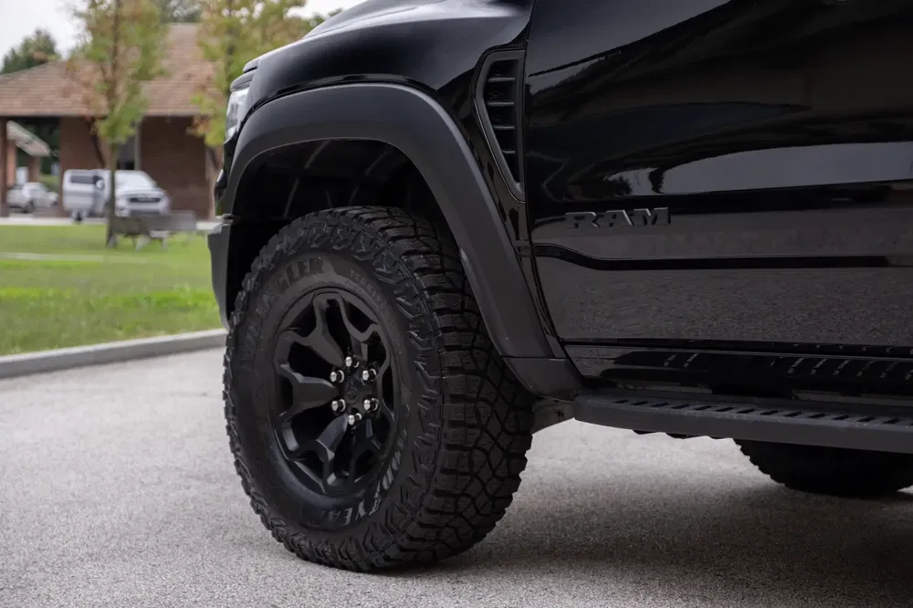 Detail van een moderne zwarte RAM pick-up met robuuste wielen in stedelijke omgeving.
