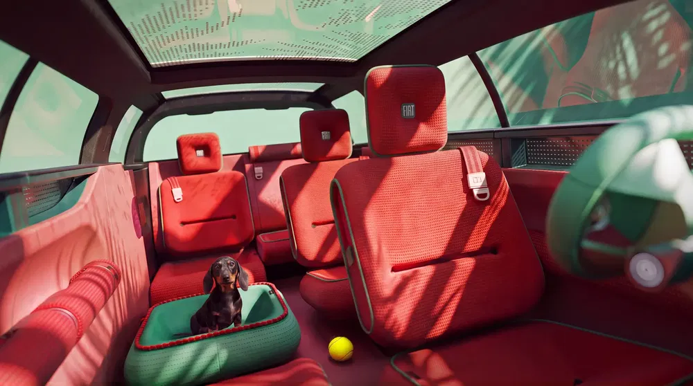 Fiat auto-interieur met moderne rode stoelen en een hond op de achterbank.