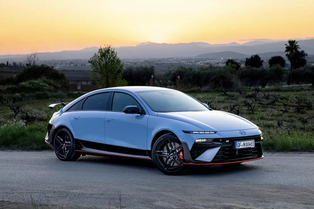 Hyundai Ioniq 6 électrique avec design élégant au coucher de soleil, sur route de campagne.