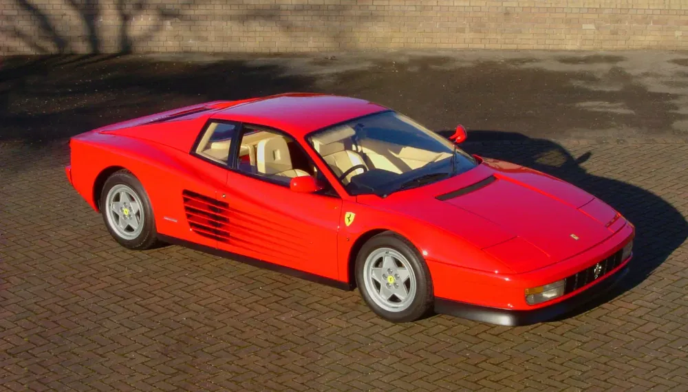 Rode Ferrari Testarossa geparkeerd op bestrating, bovenaanzicht.