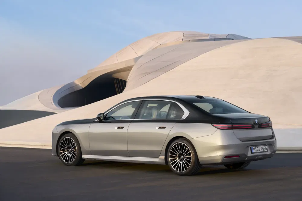 Grijze BMW sedan geparkeerd voor een modern gebouw met futuristische vormen.