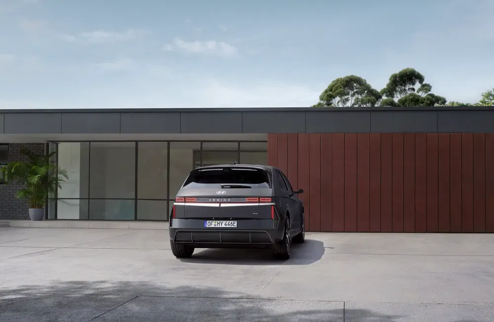 Hyundai Ioniq 5 geparkeerd voor modern huis, met heldere lucht op de achtergrond.