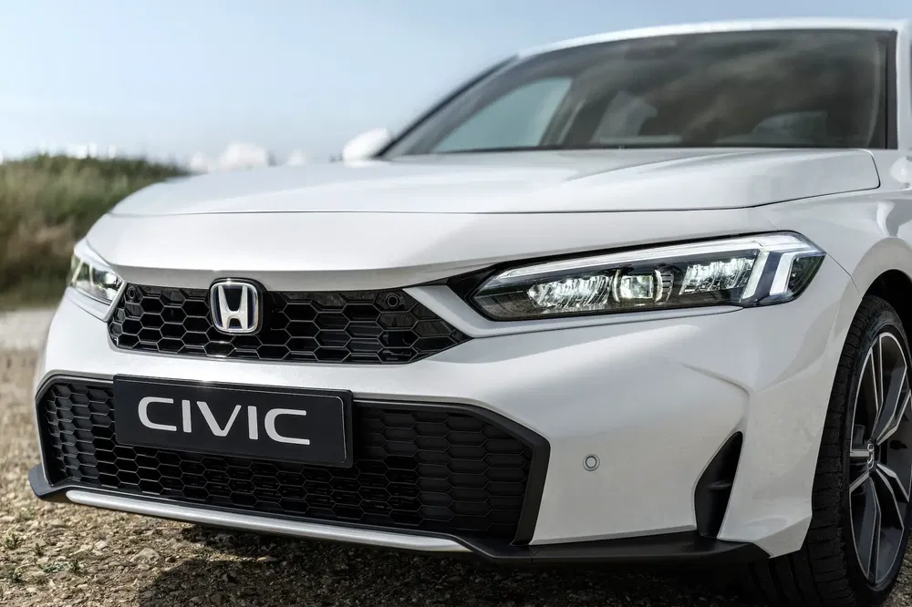 Honda Civic blanche vue de face avec calandre distincte et phare LED moderne.