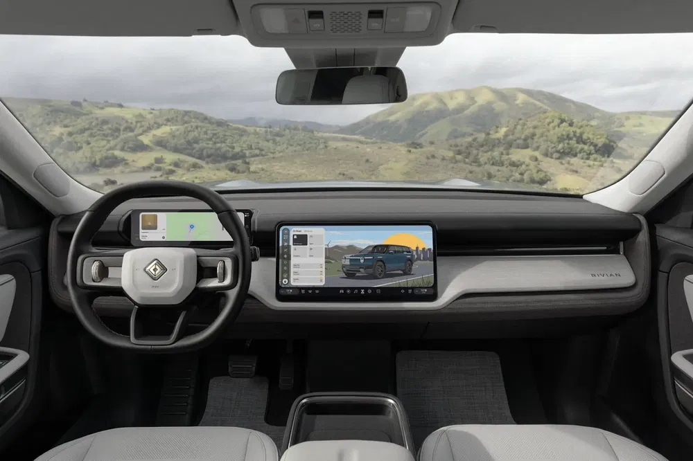 Intérieur moderne d'un Rivian avec un tableau de bord numérique et vue panoramique.