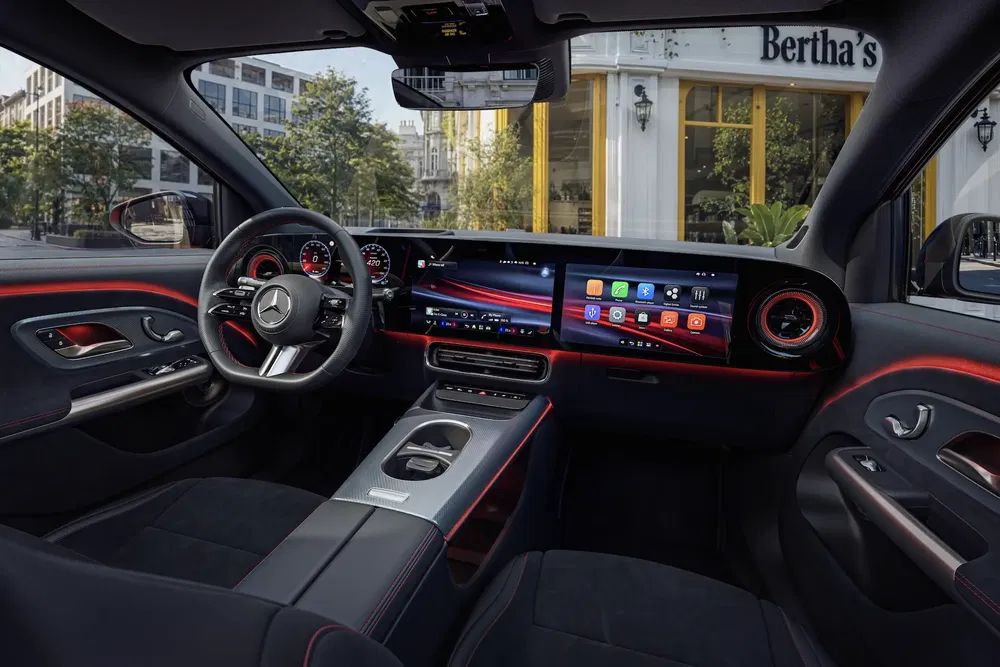 Luxe binnenkant van een Mercedes auto met touchscreen, ergonomisch stuur en sfeerverlichting.