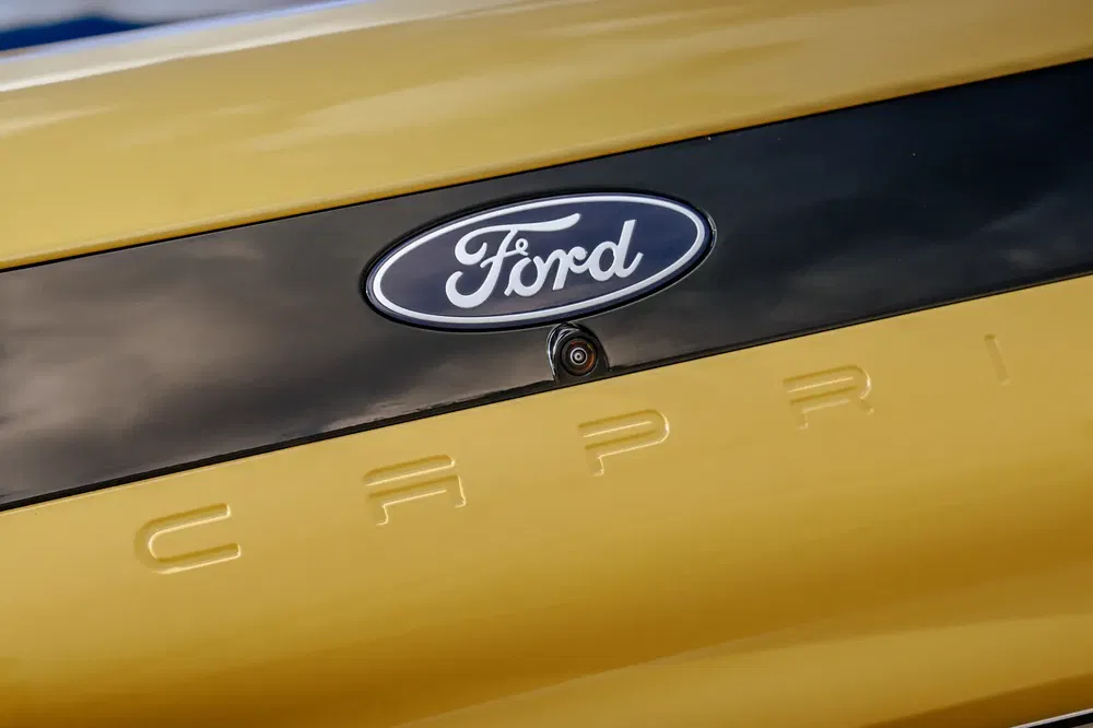 Logo Ford sur une Ford Capri jaune, emblématique voiture classique.