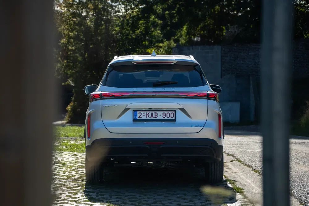 Vue arrière d'un SUV Chery gris stationné sur une rue pavée, plaque belge visible.