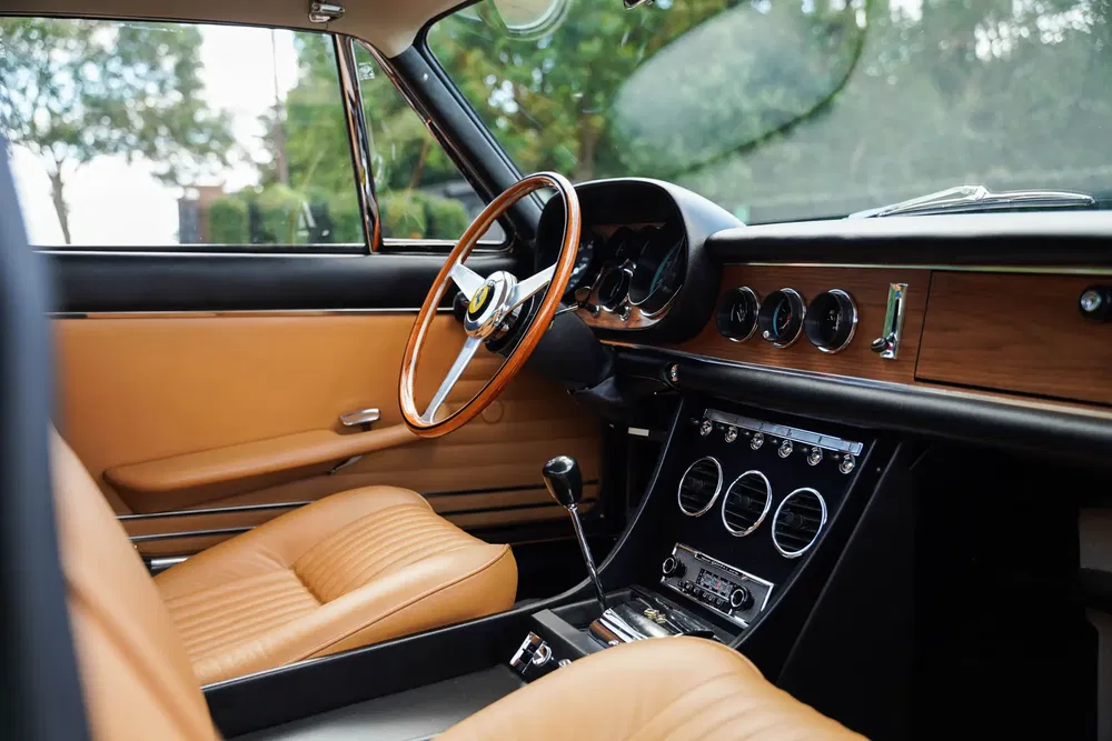 Intérieur classique d'une voiture de collection avec volant en bois et sièges en cuir beige.