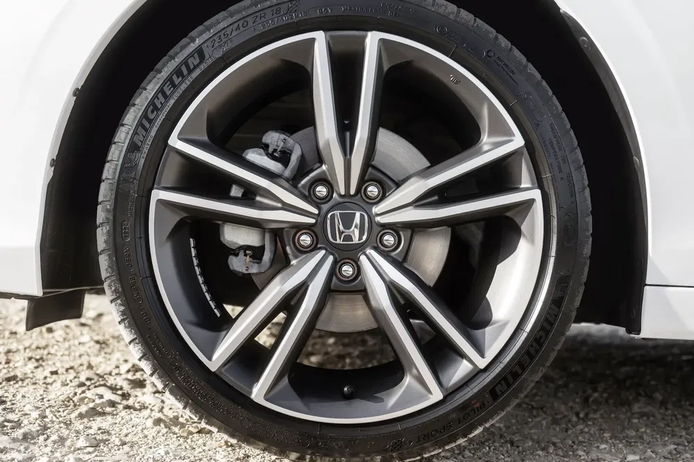 Jante de voiture Honda en alliage avec pneu Michelin sur sol graveleux.