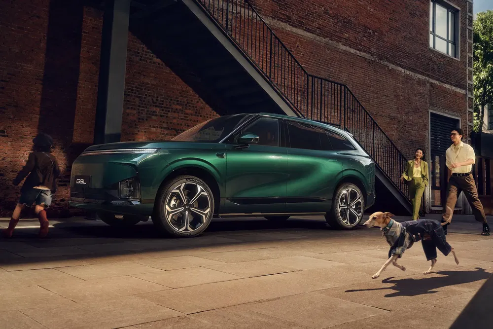 SUV vert Geely Emgrand 2024 stationné près d'un bâtiment en briques, design moderne.