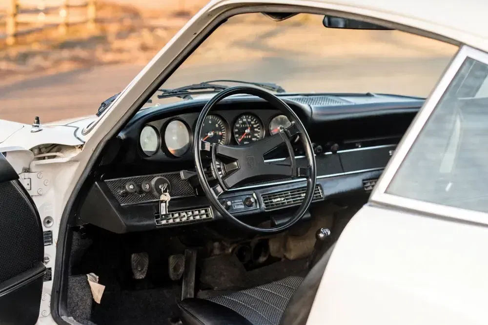 Intérieur d'une Porsche 911 classique avec tableau de bord vintage et volant iconique.