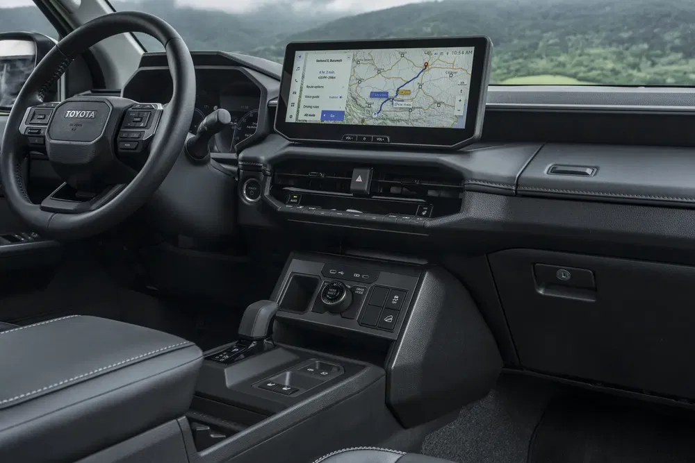 Intérieur Toyota avec volant moderne et écran tactile GPS, affichant chemins et options.