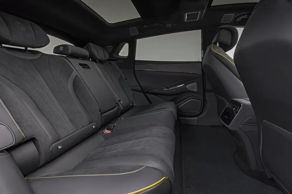 Luxe interieur van een moderne auto met leren stoelen en gele accenten.