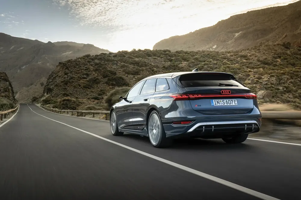 Audi SQ7 gris sur route de montagne, ciel dégagé, paysages rocailleux, allure sportive.