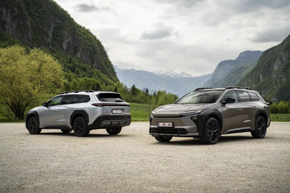 Deux SUV modernes garés dans un cadre montagneux verdoyant.