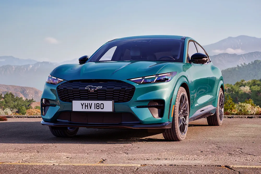 Ford Mustang Mach-E électrique vert en plein air avec montagnes en arrière-plan.