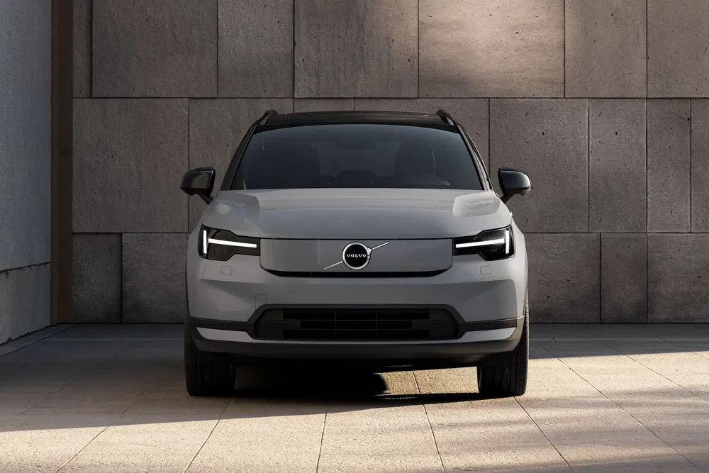 Vue avant du SUV Volvo EX30 gris devant un mur en béton.
