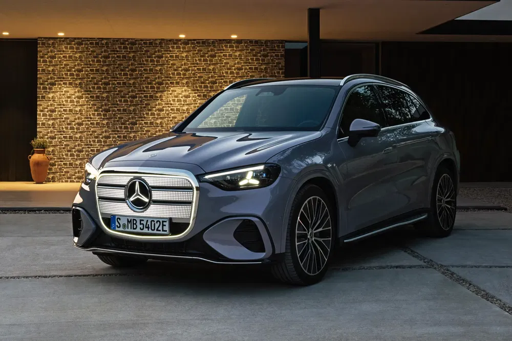 Elektrische Mercedes-Benz EQS SUV geparkeerd voor een moderne woning, verlicht in de avond.