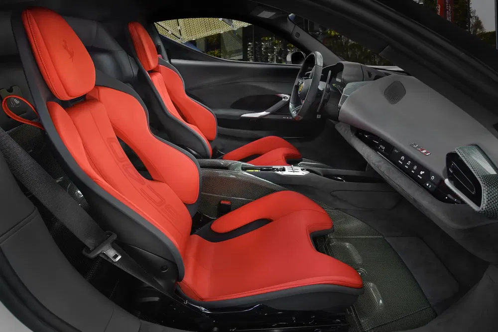 Intérieur de Ferrari SF90 Stradale avec sièges sport rouges et tableau de bord moderne.