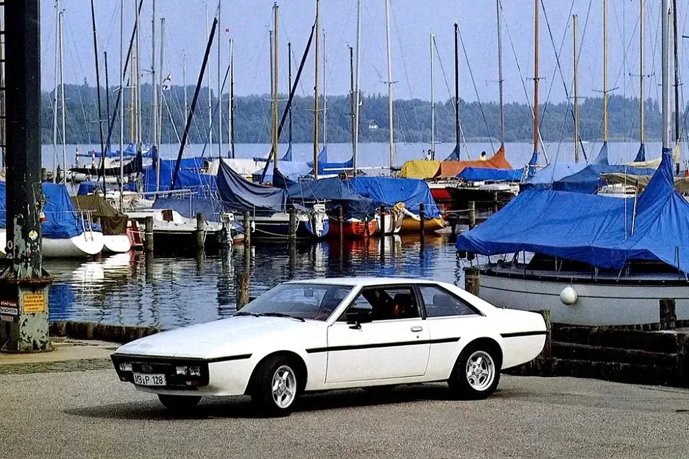 Witte vintage auto MGB GT Station, haven met zeilboten op de achtergrond.
