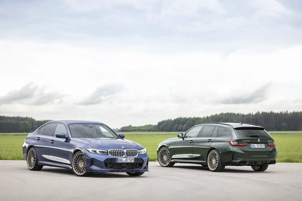 Deux voitures BMW Alpina garées dans un paysage champêtre, une berline bleu et un break vert.