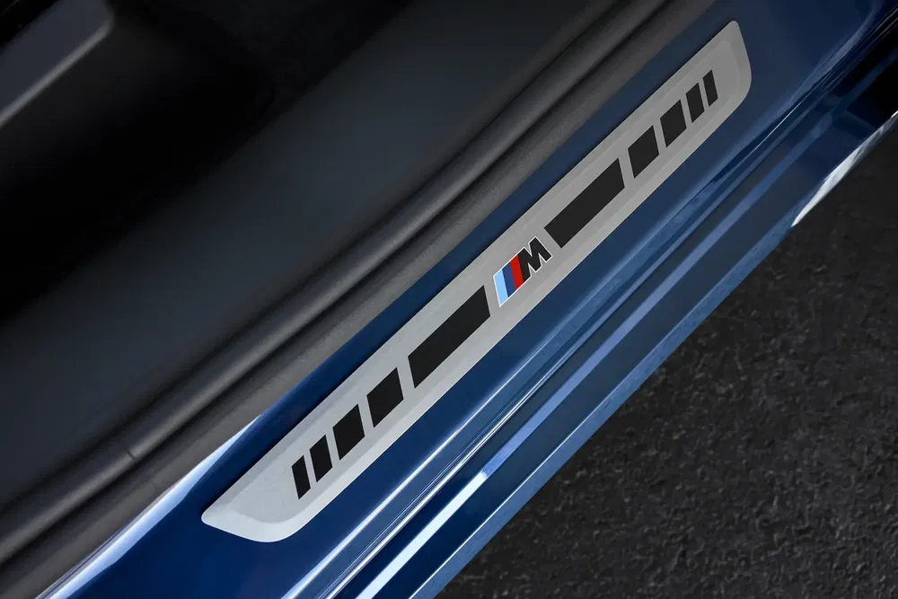 Seuil de porte BMW M en métal sur carrosserie bleue.