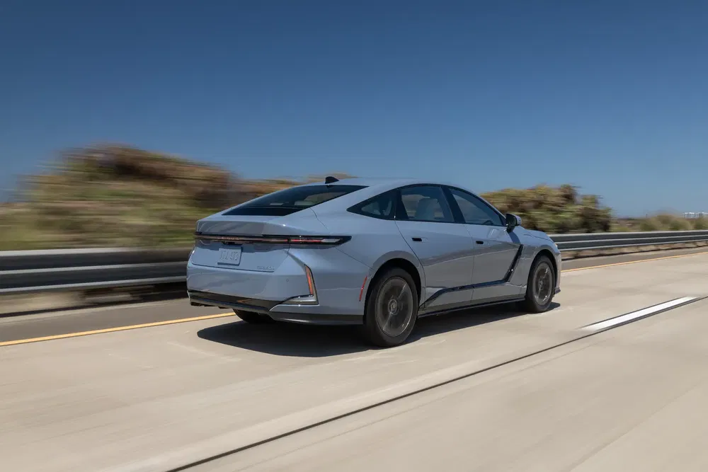 Berline électrique Lucid Air en mouvement sur une autoroute ensoleillée, vue arrière dynamique.