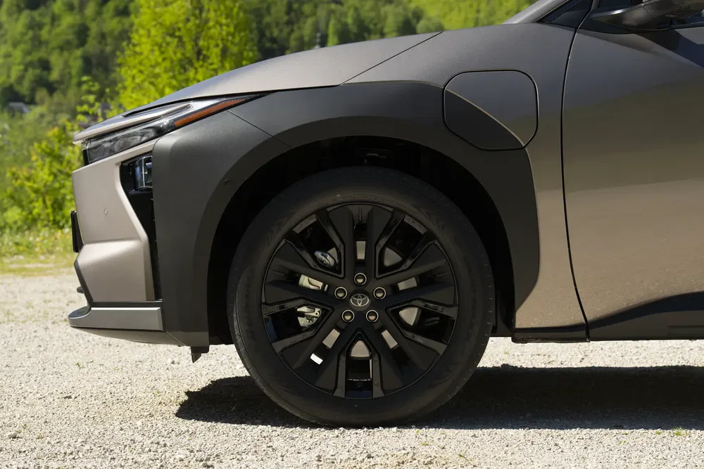 Détail de la roue du Toyota bZ4X électrique sur fond de nature verdoyante.