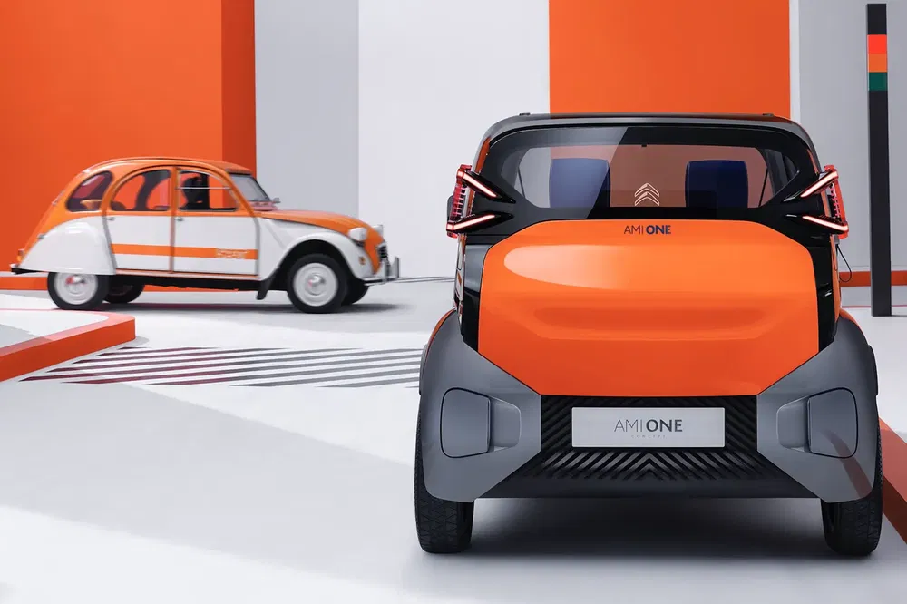 Voitures Citroën Ami One et 2CV dans un garage moderne orange et blanc.