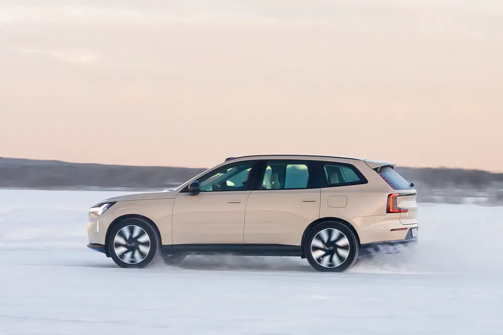 SUV Volvo beige roulant sur la neige à grande vitesse, horizon dégagé en arrière-plan.