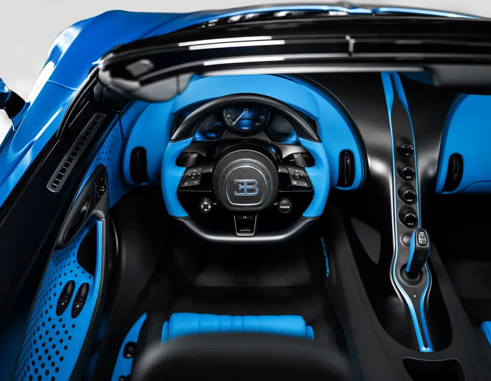 Intérieur luxueux de la Bugatti Chiron, volant et console centrale en bleu et noir.