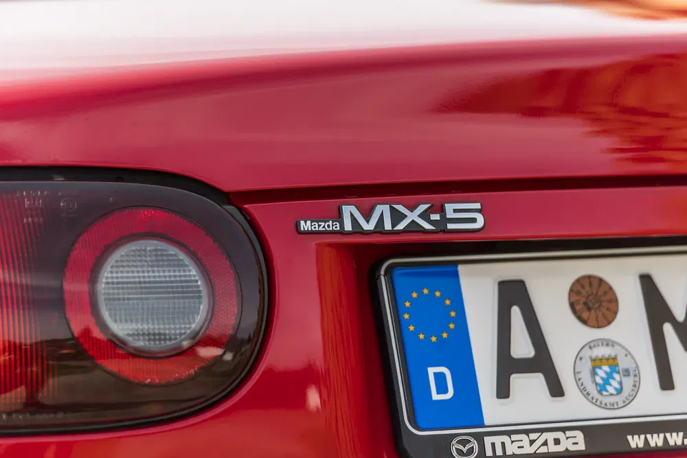 Détail arrière de Mazda MX-5 rouge avec plaque d'immatriculation européenne et feu arrière.