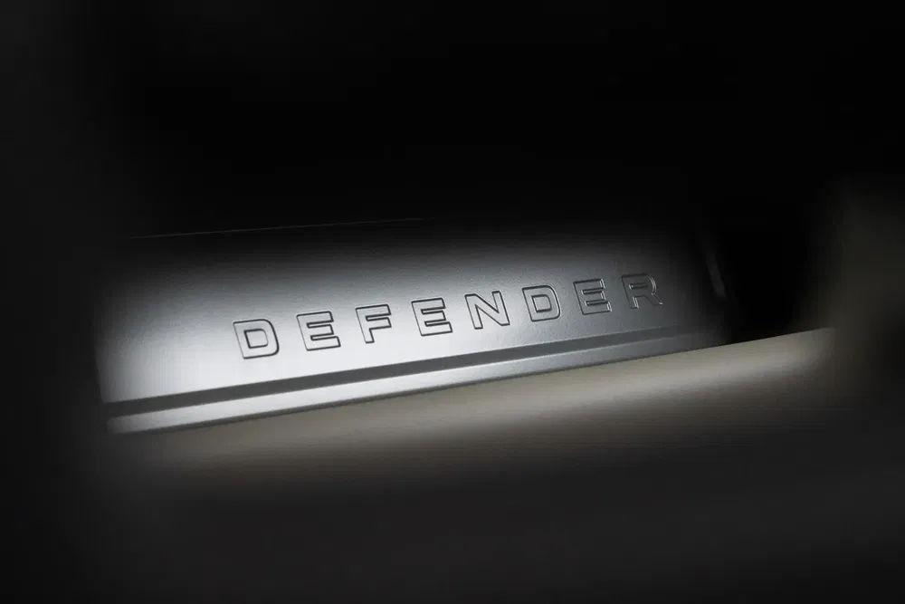 Logo de seuil de porte Land Rover Defender en gros plan et éclairé.